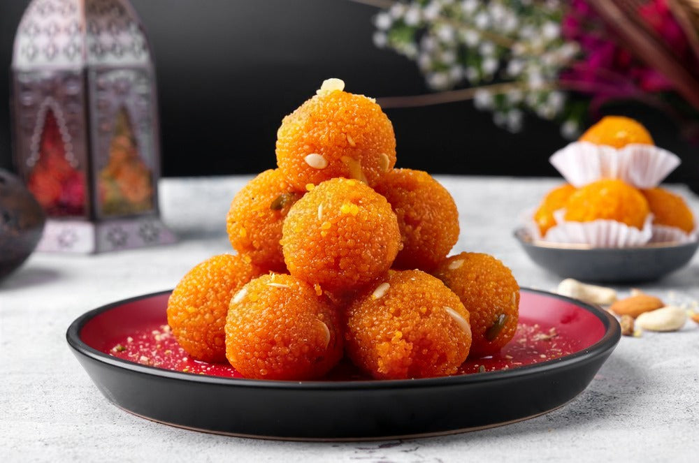 Stack Of Motichoor Ladoo Made By Lynk Foods On A Red And Black Plate.